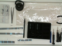 A set of additional spare parts for the game console: 4 stickers, a set of small bolts, tweezers, 6 additional buttons, a stylus, 4 screwdrivers of different sizes, a light gray sticker for the console, 2 plastic styluses