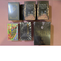 Set of 7 Sublime Thresholds Tarot, Emerald Tarot, Playful Heart Tarot Obscuro Tarot by Lotta Glybotskaia Emerald Papyrus Tarot, and Ora Tarot Guidebook