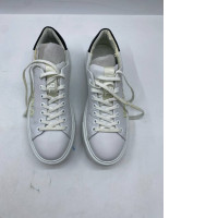 Low-top white leather sneakers with a black stripe on the heel and white laces.