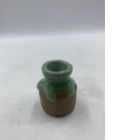A small sculpture, glazed green on the neck and shoulders, resembles a miniature vase or pot. A small sculpture, glazed green on the neck and shoulders, resembles a miniature vase or pot.