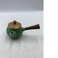 Green teapot with wooden handle on the side.