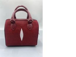Red faux stingray leather handbag with rolled-up top handles and a top zipper closure.