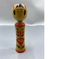 vintage Japanese Kokeshi doll is a traditional wooden figurine, likely from the Naruko region, featuring hand-painted red floral motifs and a distinct round head. 