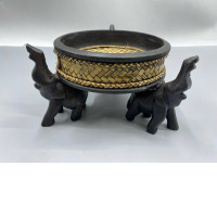 a handcrafted Thai wooden and rattan bowl supported by carved elephant figures, often used for decorative purposes or serving snacks. 