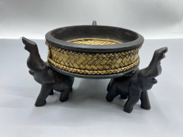 a handcrafted Thai wooden and rattan bowl supported by carved elephant figures, often used for decorative purposes or serving snacks. 