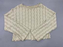 A sheer beige knitted sweater with distressed details, similar to designs from Zara or Comme des Garçons Homme Plus.