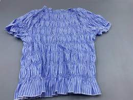 The Damson Madder Becca blouse is characterized by its pleated bodice, puffed sleeves, and stripes.