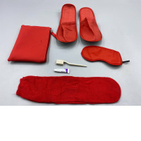 A red hotel amenity set, consisting of a storage bag, slippers, eye mask, toothbrush, and toothpaste.