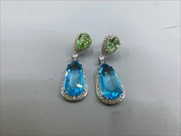 These dangling earrings are distinguished by pear-shaped peridot green crystals.