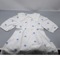 white dress featuring blue flower embroidery and a large collar.