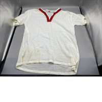 A traditional or indigenous-style white linen shirt with red embroidery detail around the V-neck. A traditional or indigenous-style white linen shirt with red embroidery detail around the V-neck.