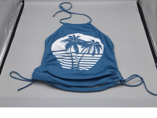 blue halter tankini top features a white graphic of palm trees over a striped horizon and has adjustable side-tie details. blue halter tankini top features a white graphic of palm trees over a striped horizon and has adjustable side-tie details.