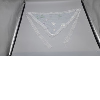 A white, triangular headscarf, known as a mantilla, used for religious ceremonies often features embroidered floral patterns on a light, translucent mesh fabric.