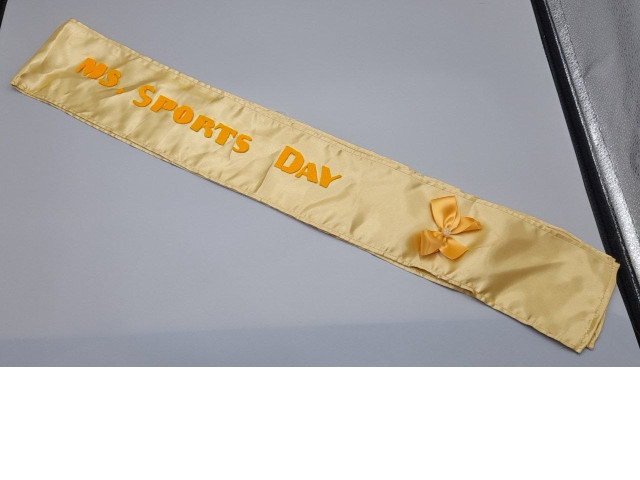 personalized gold satin sash featuring the text "NS SPORTS DAY" and a decorative bow personalized gold satin sash featuring the text "NS SPORTS DAY" and a decorative bow