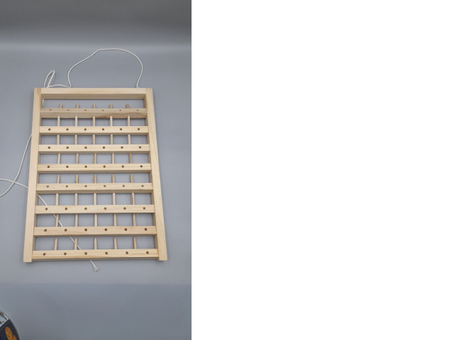 A wall-mounted wooden thread rack, commonly used for storing spools of sewing thread. A wall-mounted wooden thread rack, commonly used for storing spools of sewing thread.